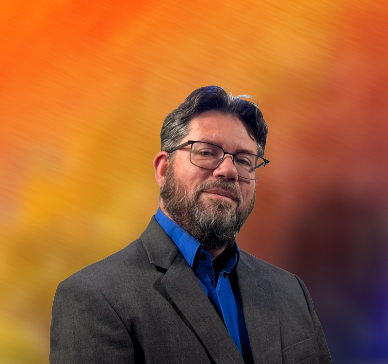 Our founder, a middle-aged white dude with short brown hair, wearing a blue dress shirt and gray coat.